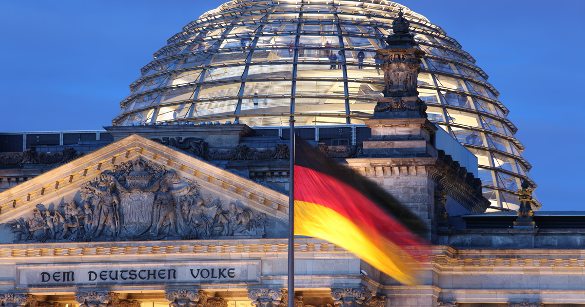 Das Gebäude des Reichstags mit der Flagge der Bundesrepublik Deutschland im Vordergrund