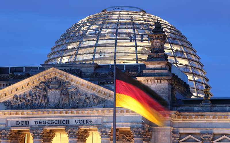 Das Gebäude des Reichstags mit der Flagge der Bundesrepublik Deutschland im Vordergrund